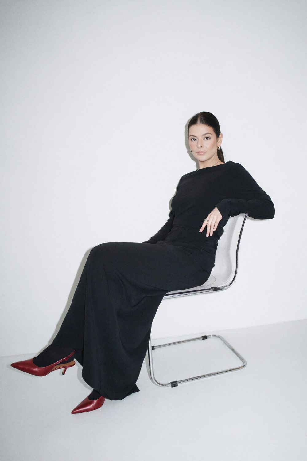 Dra. Isabelle Tobias sentada em cadeira transparente, vestido preto